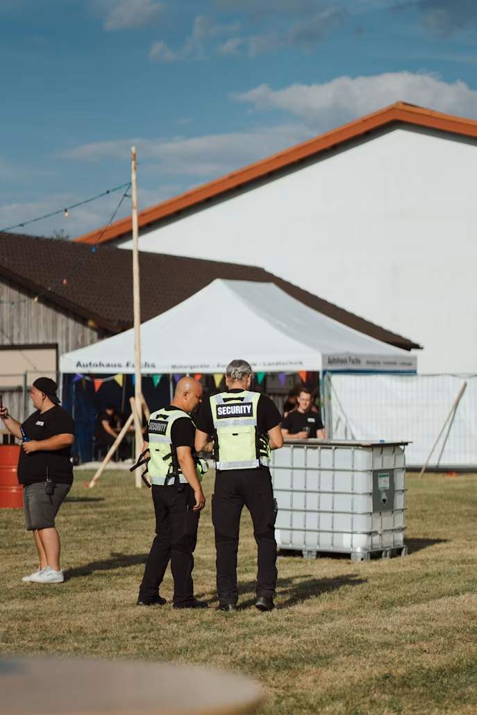 two security guards wearing green vests standing together at an event