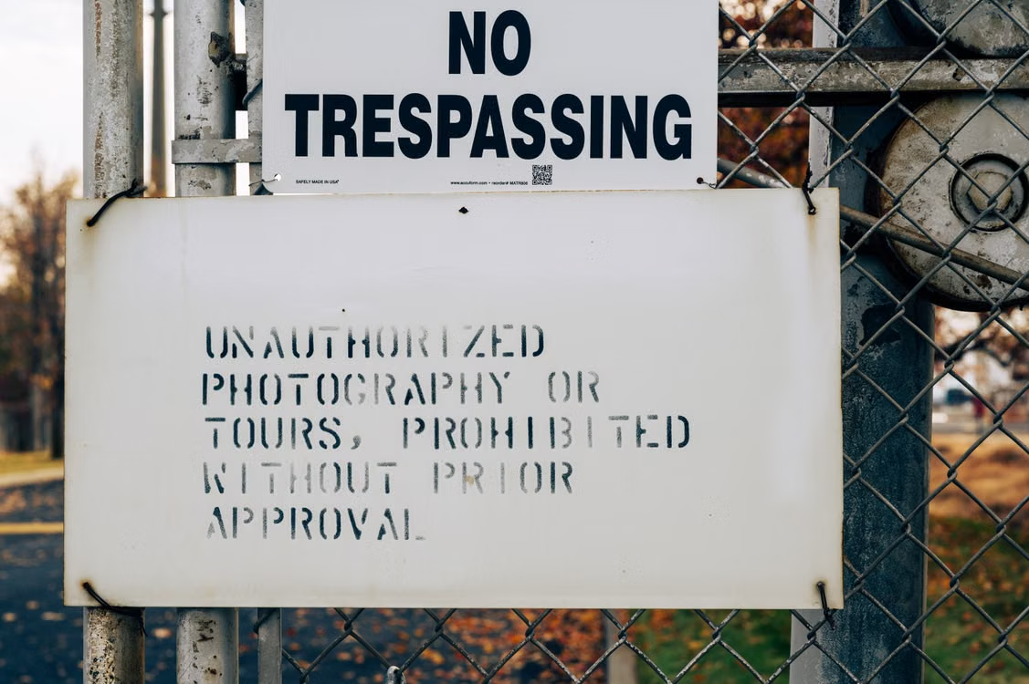 no trespassing sign on a wire mesh fence