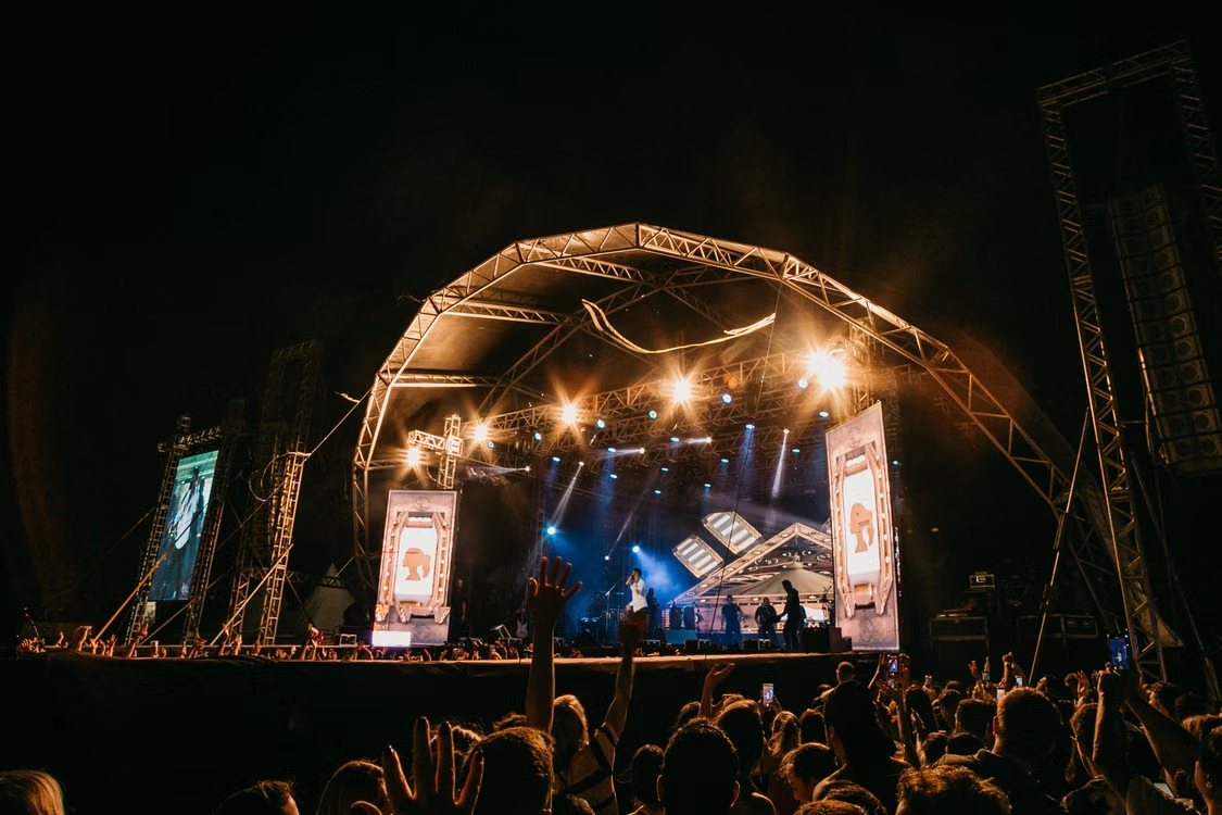Large crowd gathered in front of an illuminated stage during an event.
