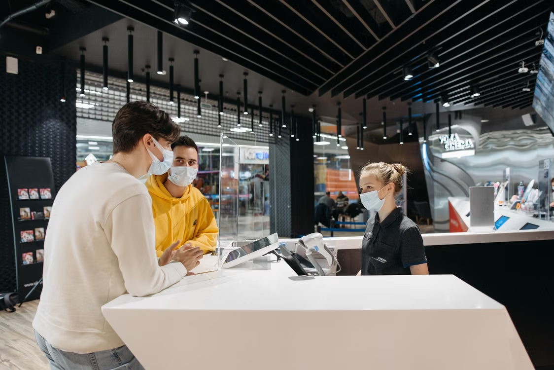Store representative assisting customers at a retail store service counter.