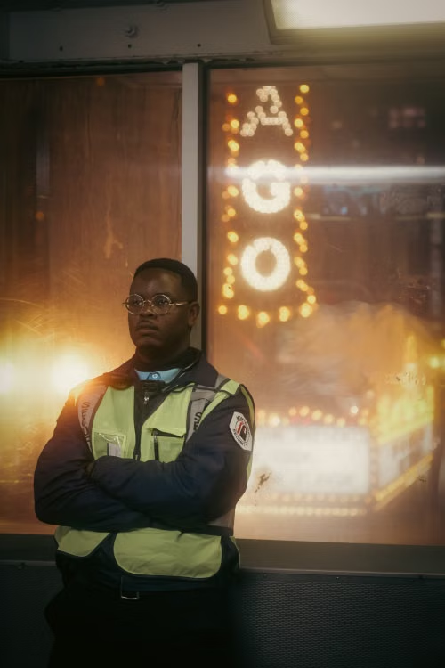 Uniformed security guard standing watch outside a property entrance during night hours.